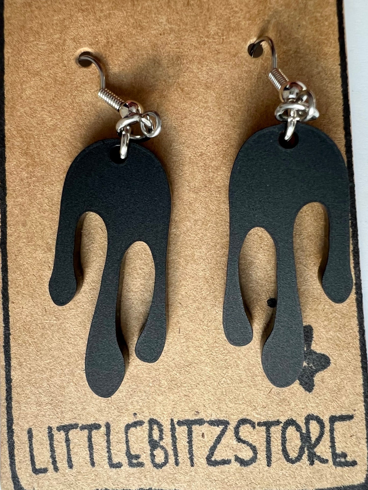 Transparent matte black colored earrings in a drip design, made with acrylic and surgical stainless steel